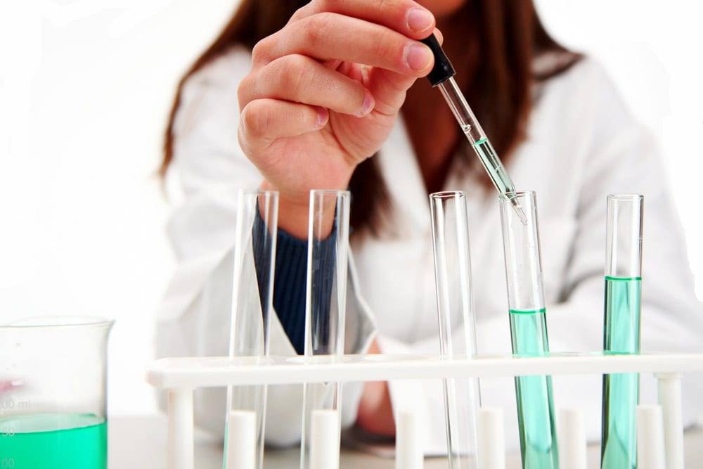 Eine Hand im Labor tropft mit einer Pipette Flüssigkeit in ein Reagenzglas