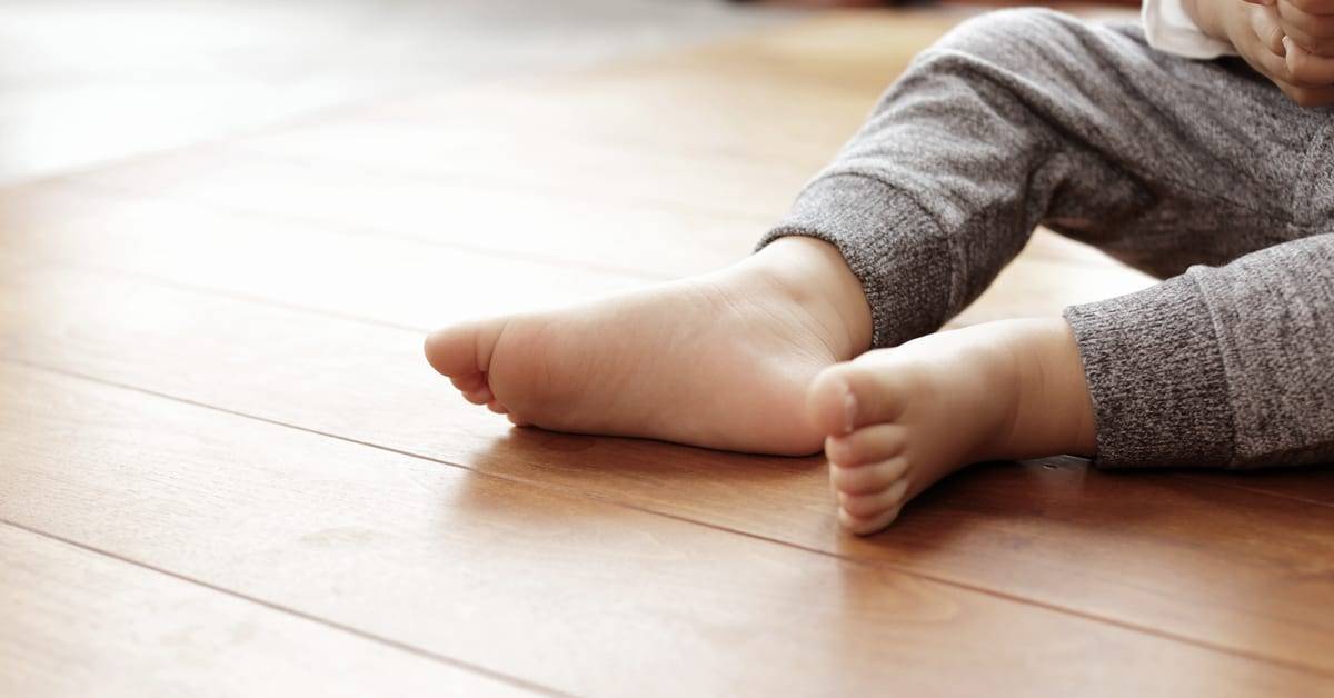 Nackte Kinderfüße auf einem hellen Boden in Holzoptik